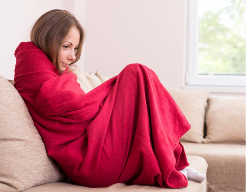 A woman wrapped up in a blanket considering calling Hometown Heating for Emergency Heating Service